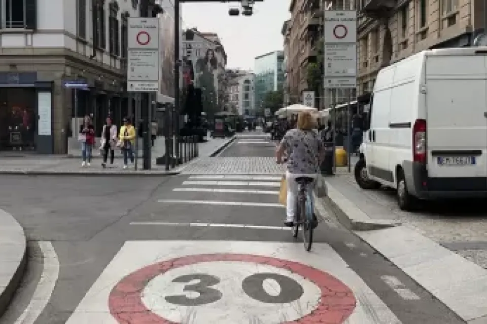 A bike rider navigates a bike lane in a traffic limited zone in Italy, where only one delivery van is visible on the street.